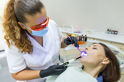 A dental hygienist performing a cleaning procedure on a patient s teeth using a dental pick and brush.