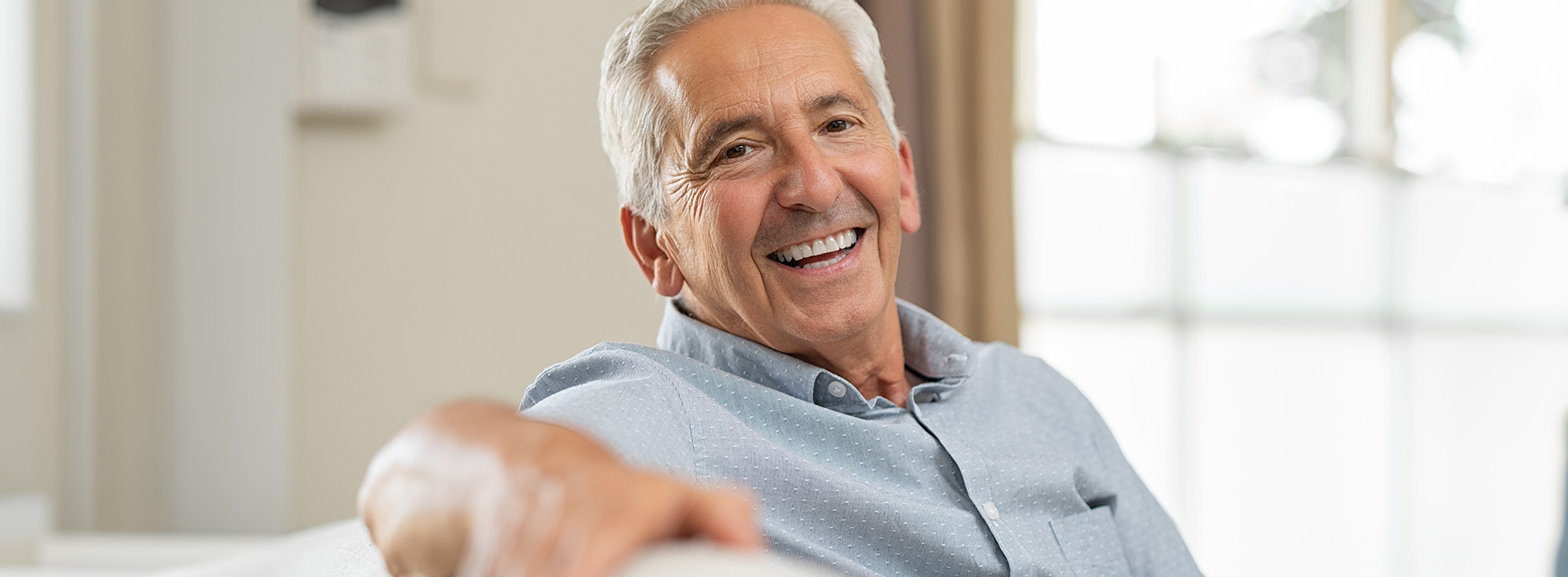 A man sitting comfortably with his arm resting on a table, smiling at the camera.