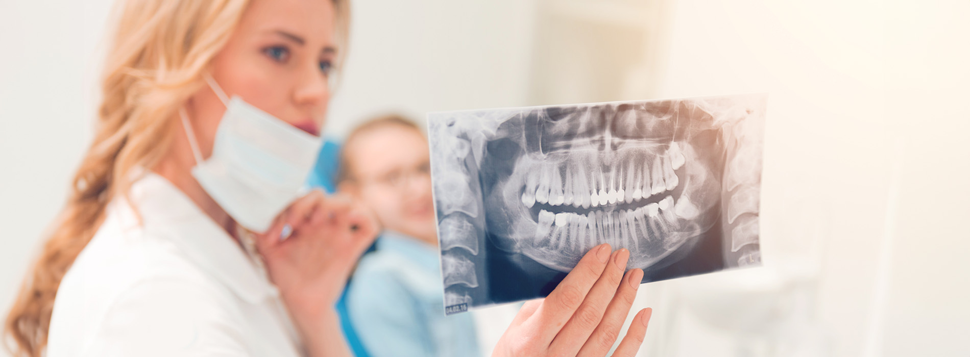 The image shows a dental professional holding up an X-ray film with a patient s mouth, while another individual appears to be assisting with a medical device, set against a clinical background.