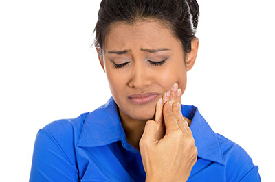 A woman with her eyes closed, holding her nose and looking upwards, appears to be experiencing discomfort or pain.