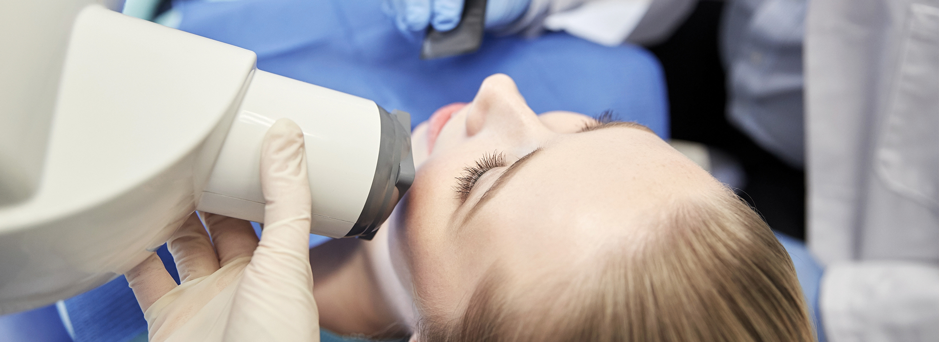 A person receiving dental treatment with a dentist using a microscope to examine their mouth.