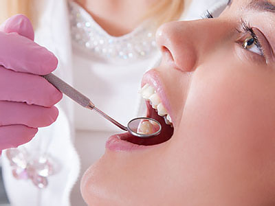 An individual receiving dental treatment from a professional using dental instruments.