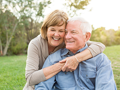 A man and woman embracing each other outdoors.