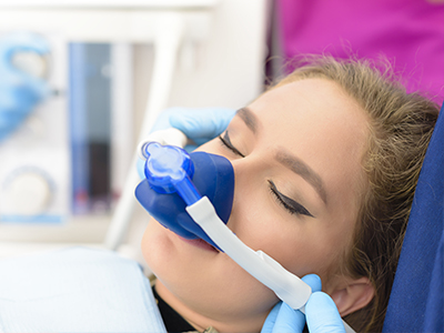 The image shows a person receiving medical attention with a medical device attached to their face while lying on a hospital bed.